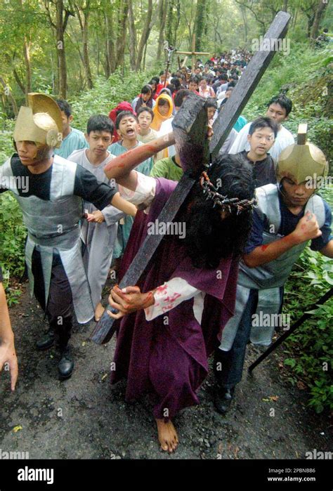 An Indonesian Man Portraying Jesus Christ Carries A Wooden Cross During