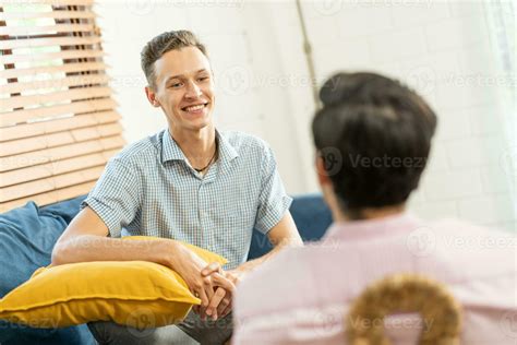 Loving Same Sex Male Couple Lying On Sofa At Home Watching Tv And Relaxing Together Homosexual