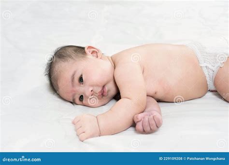 Portrait Of A Cute Little Baby Boy In Diaper Lying On White Bedthe