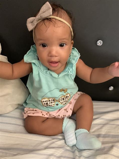 A Baby Girl Sitting On Top Of A Bed