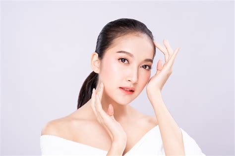 美しさできれいな新鮮な白い肌の顔を持つ美しい若いアジア女性は、指で肩に触れるポーズします。 プレミアム写真