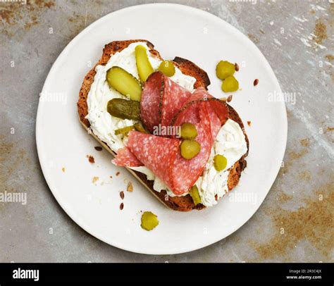 Open Faced Sandwich With Cream Cheese Salami And Pickles Stock Photo