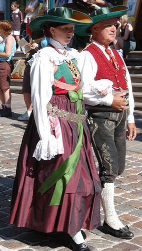 Two People Dressed In Period Clothing Standing On The Side Of A Brick