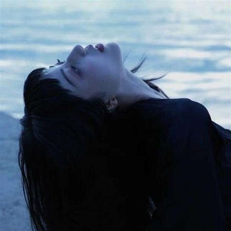 A Woman With Her Eyes Closed Laying On The Ground Next To Water And