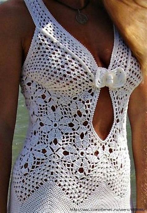 A Woman Wearing A White Crochet Swimsuit Standing Next To The Ocean