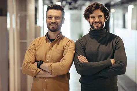 Portrait Of Two Cheerful Entrepreneurs Posing With Crossed Arms And