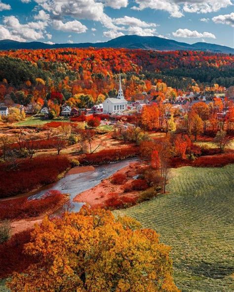 An Aerial View Of A Small Town Surrounded By Trees With Autumn Foliage