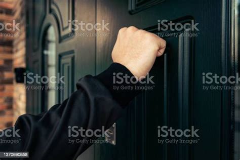 Man Hand In A Black Jacket Knocks On A Dark Green Wooden Door Anybody