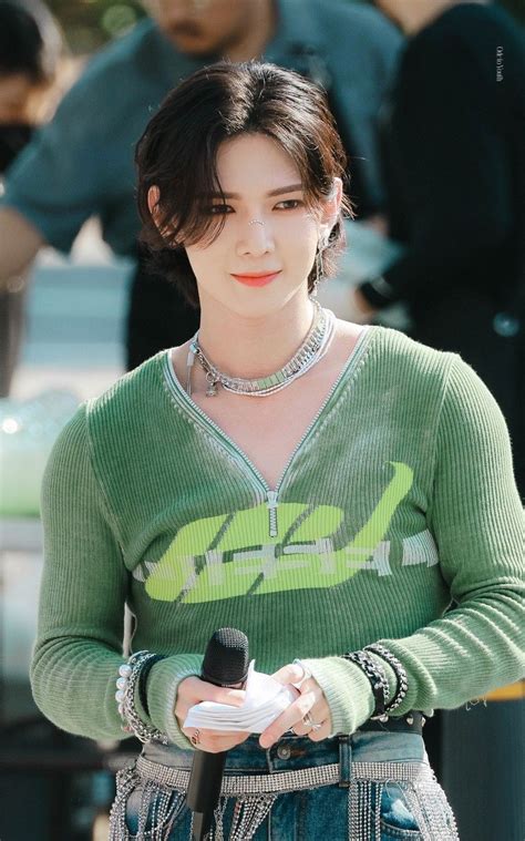 A Woman Wearing A Green Sweater And Holding A Cell Phone In Her Hand