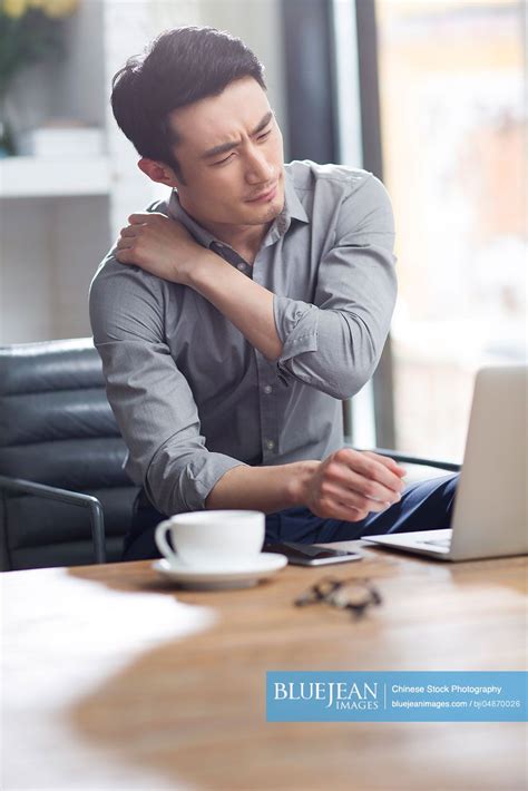 Tired Young Chinese Man Working In Office High Res Stock Photo For Download