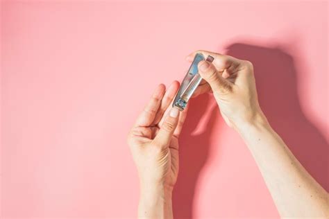 Premium Photo Close Up Of Woman Cutting Nails Against Pink Background