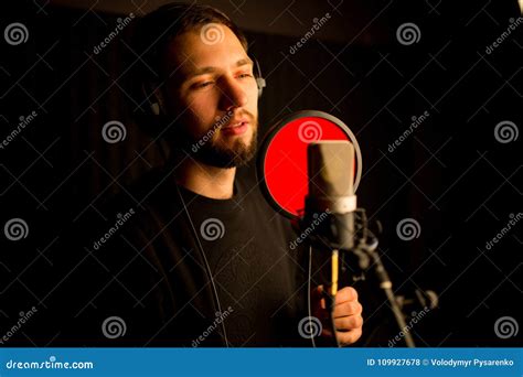 Male Vocalist Singing Into Microphone In Recording Studio Creating New