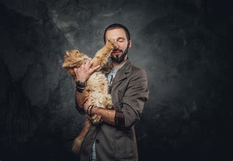 El dueño de la mascota en el blazer sostiene un gato grande y esponjoso