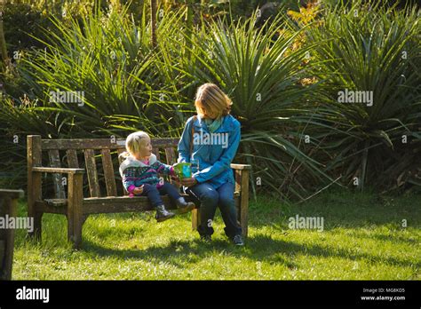 A Grandmother And Her Granddaughter Sitting On A Bench Talking Stock