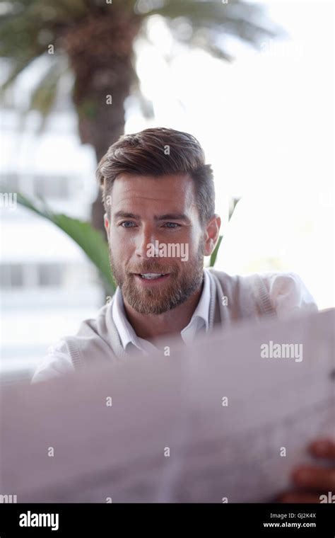 Mature Man Sitting Outside Cafe Looking At Blueprints Stock Photo Alamy