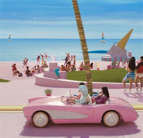 A Pink Car Parked On The Side Of A Road Next To A Beach Filled With People