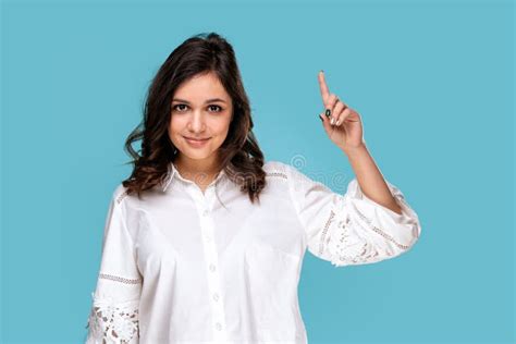 Pretty Brunette Girl Pointing Something By Finger Isolated Over The Blue Background Stockfoto