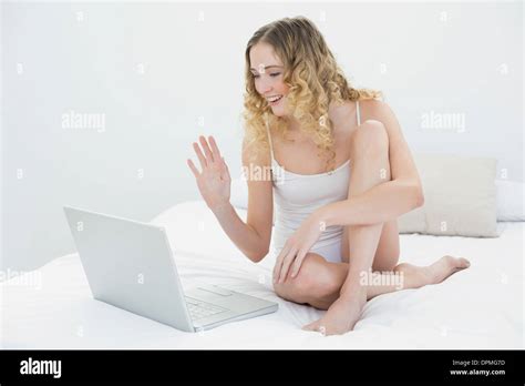 Pretty Smiling Blonde Sitting On Bed Waving At Laptop Stock Photo Alamy