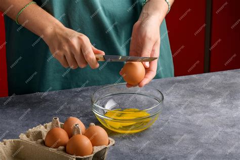 Premium Photo A Womans Hand Cracking An Egg With Knife Into A Clear