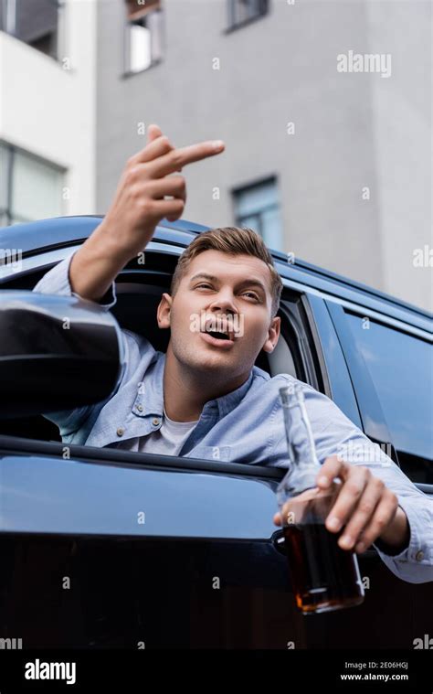 Drunk Aggressive Man With Bottle Of Whiskey Showing Middle Finger