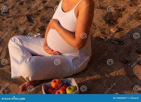 Happy Pregnant Woman With White Clothes Touching Her Belly With Love On Sunset Beach Stock Image