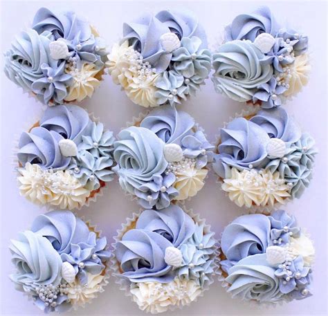 Cupcakes With Blue Frosting And White Flowers Are Arranged In A Square