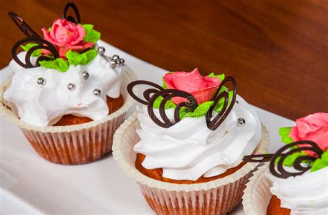 Cupcakes Decorated With Pink Rose On Wooden Background Stock Photo