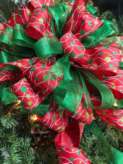 A Red And Green Christmas Wreath On Top Of A Tree