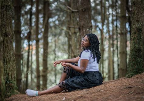 African American Woman Sitting On The Grass In A Forest Stock Image