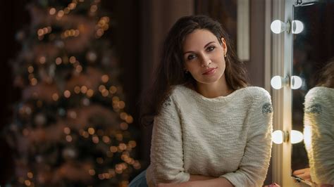 Smiley Girl Model Is Standing In Blur Christmas Tree Background Wearing White Tops And Jeans 4k