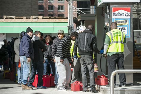 Long lines of customers on foot carrying gas cans wait to have their containers filled at the ...