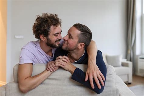 Heureux couple gay allongé sur le lit à la maison étreignant et