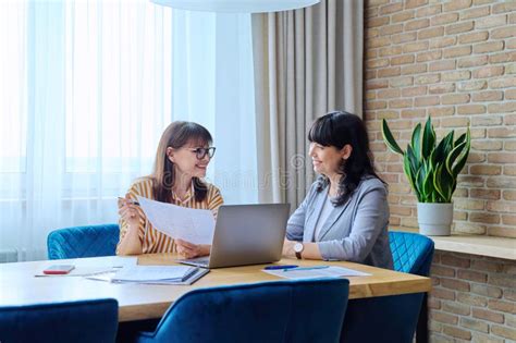 Two Mature Business Women Working In Office With Papers Laptop Stock