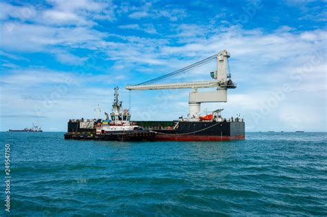 Tugboat Assists Floating Crane Transhipper In Bauxite Transshipment