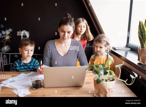 Brunette Mother Daughter And Son Using A Laptop While Mom Drinking Breakfast Coffee Stock