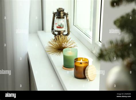 Beautiful Burning Candles And Lantern Shaped Snow Globe On Window Sill