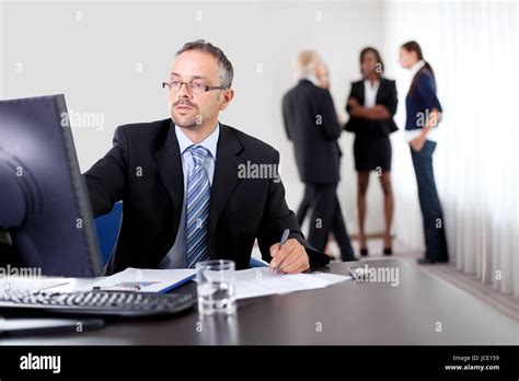 Handsome Mature Business Man Writing Notes While Using Computer At