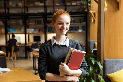 Happy Redhead Lady Student Posing Indoors In Library Holding Books