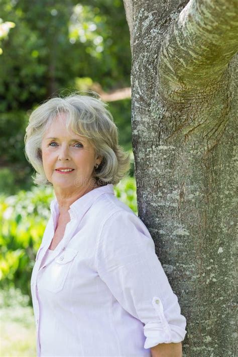 Portrait Of Mature Woman Leaning Against Tree Trunk Stock Photo Image