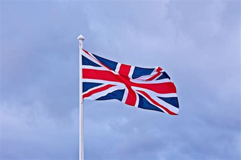 Premium Photo Waving Flag Of Great Britain Against Blue Cloudy Sky