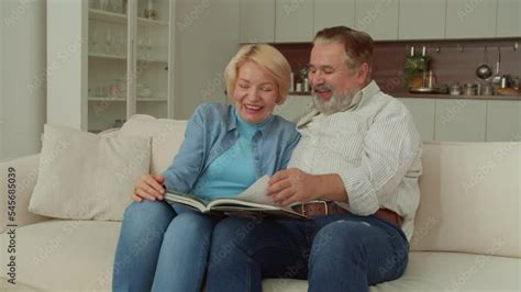Joyful Attractive Senior Woman And Cheerful Handsome Mature Man Sitting On Couch Watching