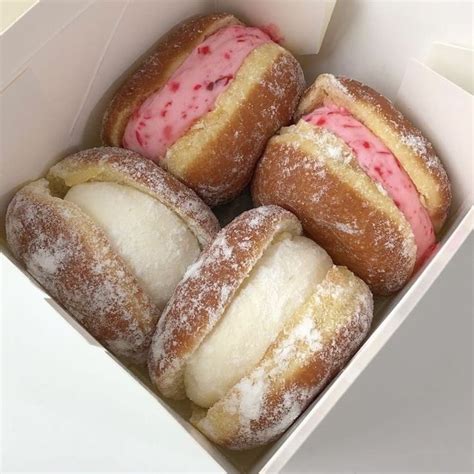 Four Donuts With Pink Frosting And Sprinkles In A White Box