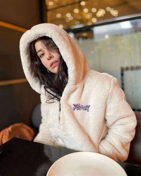 A Woman In A White Jacket Sitting At A Table With A Plate And Cup On It