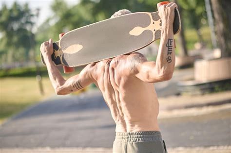 Premium Photo A Half Naked Skateboarder Holding A Skateboard