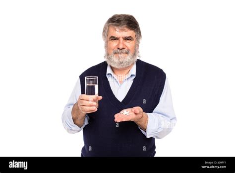 Alter Mann mit grauem Bart mit einem Glas Wasser und Pillen in Händen