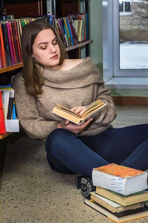 Brunette Young Girl Sitting On The Floor And Reading Book Near