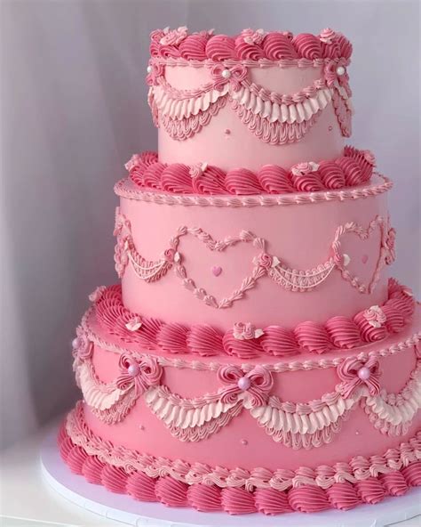 A Three Tiered Cake With Pink Icing And Hearts On It S Sides