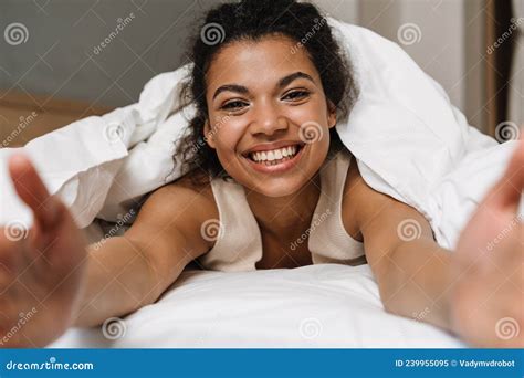 Happy Young African Woman Laying Hiding Under Blanket Stock Image