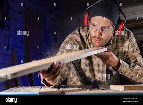 Carpenter Blowing Sawdust From Wooden Plank After Cutting With Circular