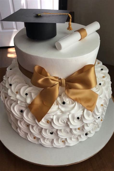 A Graduation Cake Decorated With White Icing And Gold Ribbon